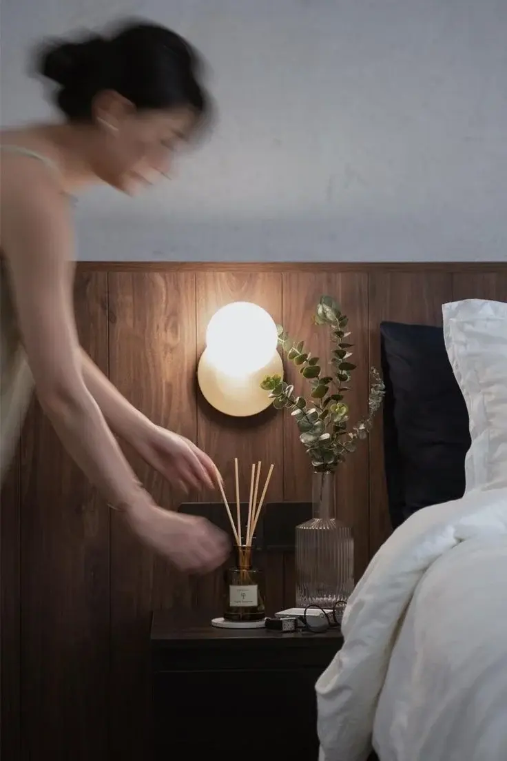 Scent stacking woman standing front bed next night stand flowers